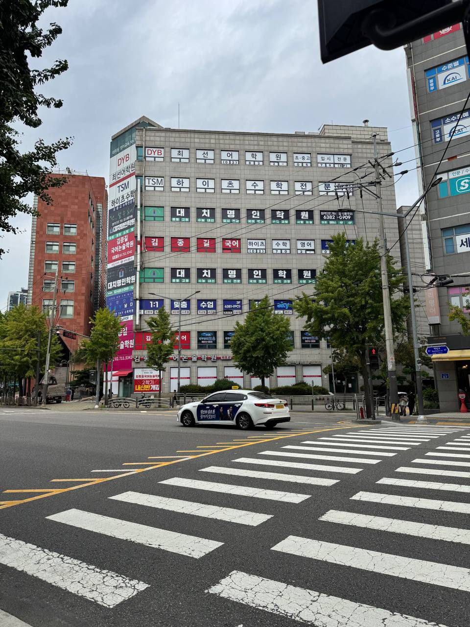 건물 외벽 가득 대치명인학원, 최선어학원, 하이츠수학, 김종길국어논술학원 간판이 층마다 붙어 있는 대흥역 학원 건물