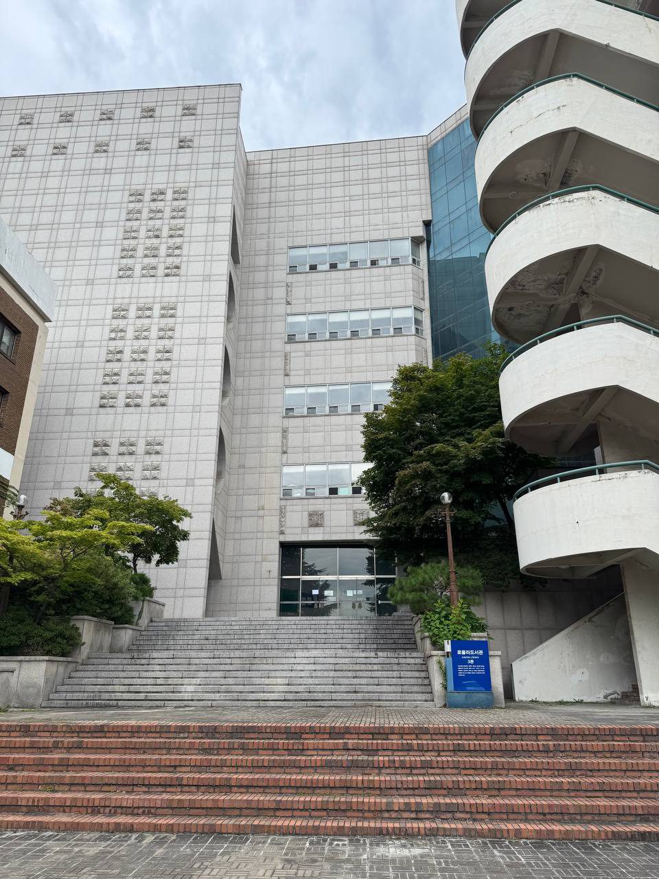 넓은 계단 위에 자리한 로욜라도서관 3관 입구와 오른쪽의 둥근 외부 계단