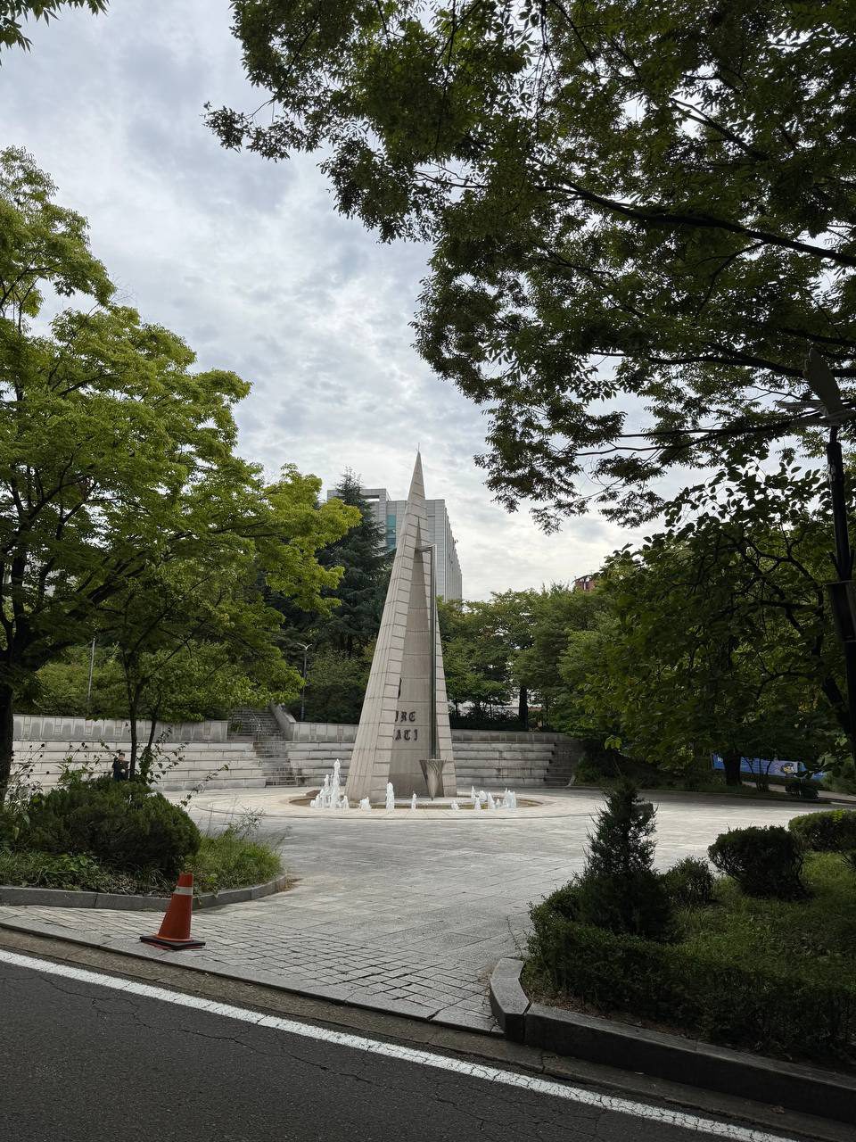 정문 앞 도로에서 바라본 알바트로스 탑, 양옆으로 짙은 나무 그늘이 드리우고 탑 뒤로 계단식 석단과 건물이 보인다