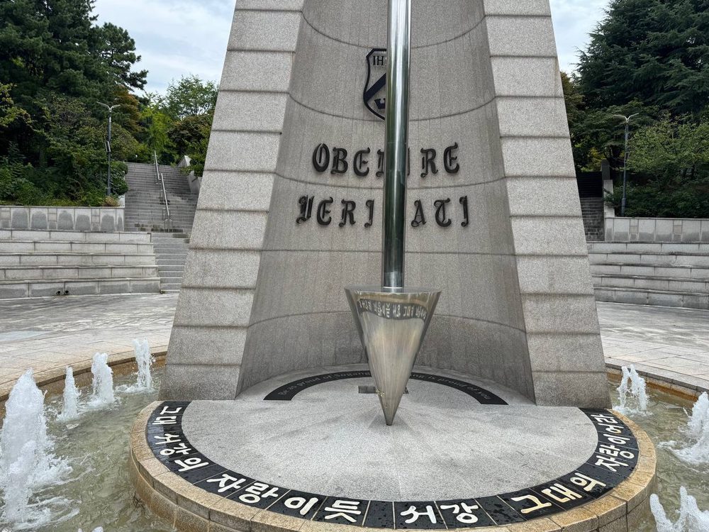 분수대 둥근 단 둘레에 검은 타일로 새긴 ‘그대 서강의 자랑이듯 서강 그대의 자랑이어라’ 글귀와 그 위로 매달린 은빛 역원뿔 추