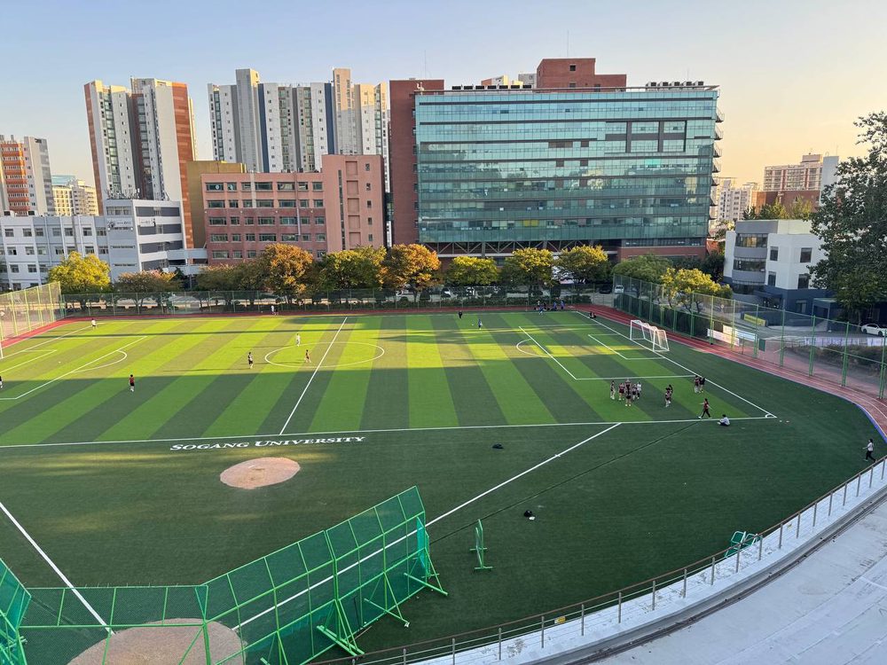 서강대 운동장 전경과 붉은 트랙, 초록색 보호망이 보이고 구장 곳곳에 사람들이 서 있다